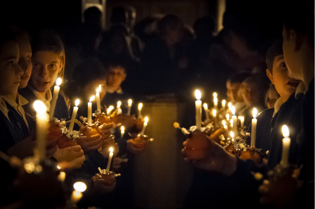 Children holding lit candles together during a community remembrance gathering